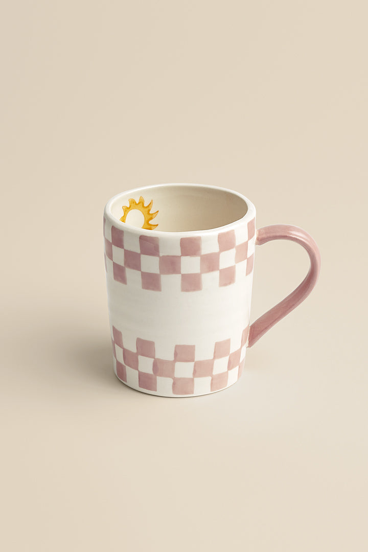 Pink stoneware mug with checkerboard and sun pattern